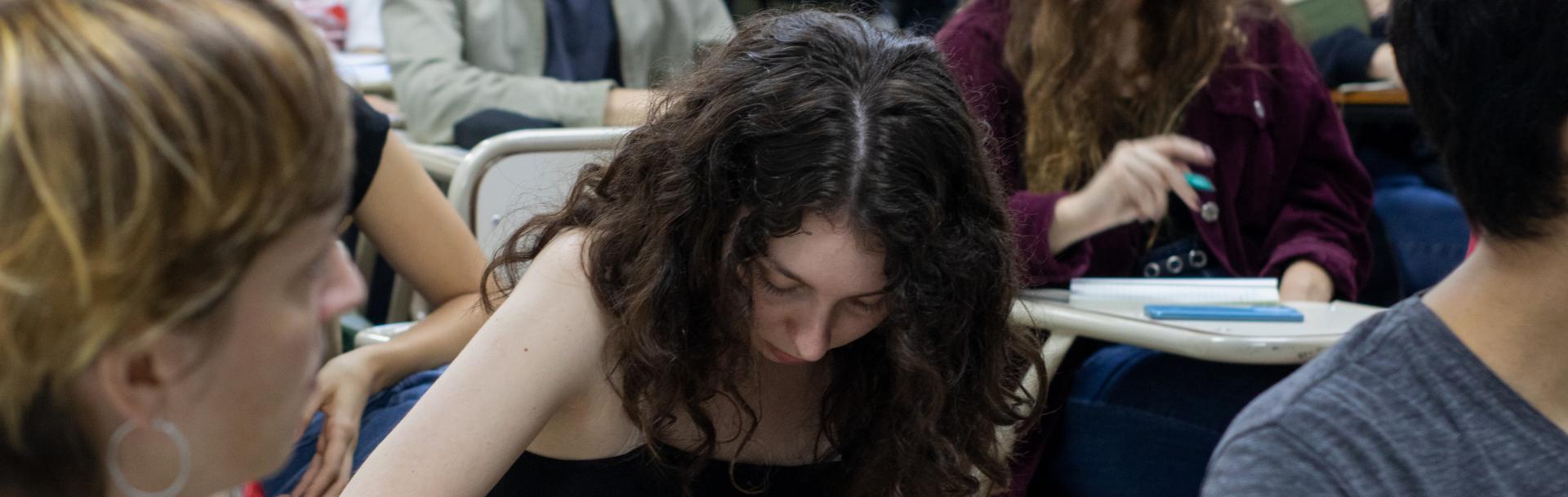 Estudiante escribiendo en un aula de la sede Puan. 